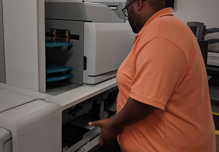 Image of Production Team member retreiving a print job from the printer.