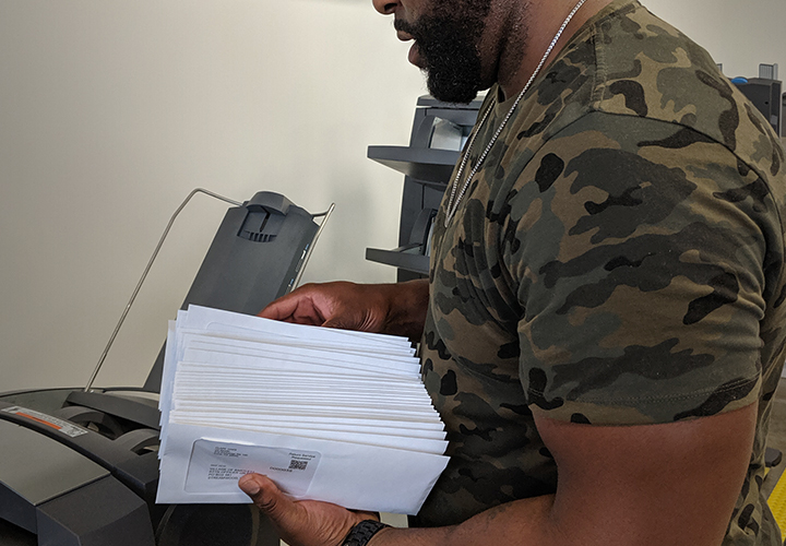 Image of Production Team member unloading letters from the envelope stuffer.